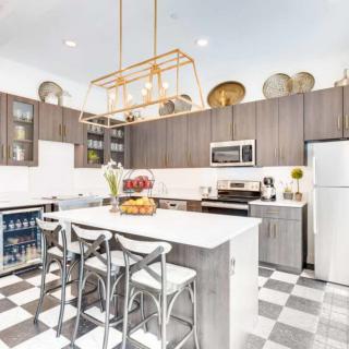 A modern kitchen with a central island, bar stools, and decorative elements on top of cabinets.