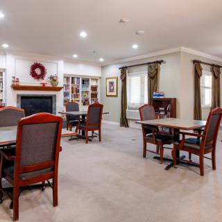 A cozy living room setup with multiple tables and chairs, featuring a fireplace and decorative elements.