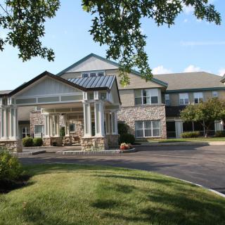 A modern residential building with a landscaped driveway and trees.