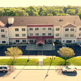 A aerial view of a multi-story residential apartment building with landscaped surroundings.