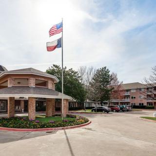 An entrance to a building complex with flags and a parking area.