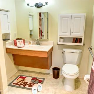 A clean and organized bathroom with a sink, toilet, and mirror.