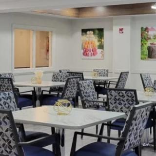 A well-lit dining area with neatly arranged tables and chairs, featuring decorative wall art.