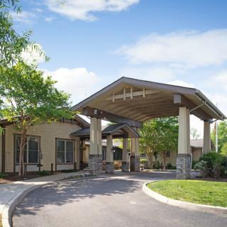 A modern building with a covered entrance nestled in a landscaped setting.