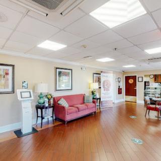 A well-lit lobby area featuring a red sofa, wooden flooring, and decorative elements.