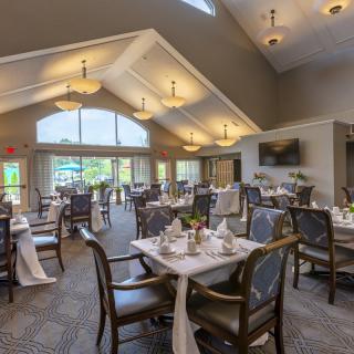 An elegant and spacious dining room with well-decorated tables and chairs, illuminated by ample natural light.