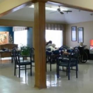 A spacious room with tables and chairs, featuring multiple windows and wall decorations.