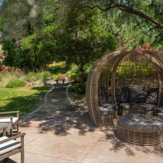 A peaceful garden patio with stylish outdoor seating surrounded by lush greenery.