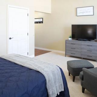 A modern bedroom with a bed, dresser, and television.