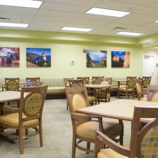 An empty cafeteria with tables and chairs, decorated with artwork on the walls.