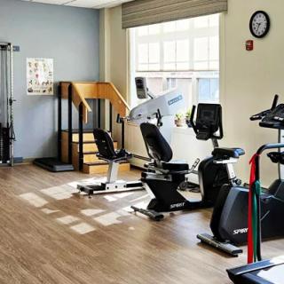 A well-lit fitness room with various exercise equipment including exercise bikes and a treadmill.