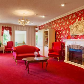 A classic living room with a red theme, featuring elegant furniture and a fireplace.