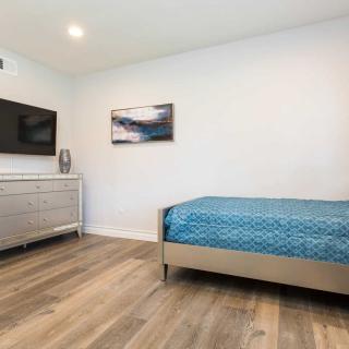 A modern, minimalist bedroom with a single bed and wooden flooring.