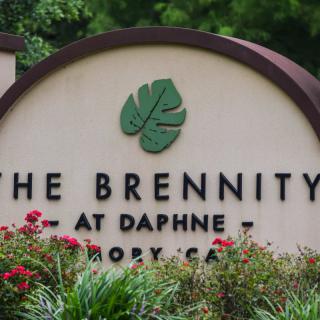 Entrance sign for The Brennity at Daphne, featuring a landscaped area with flowers.