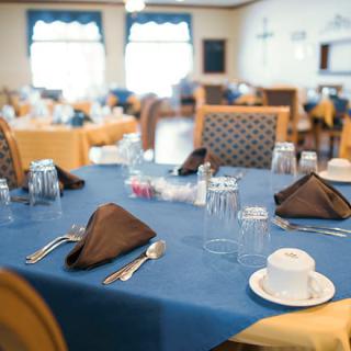 A neatly set dining table with blue tablecloth and brown napkins in a restaurant.