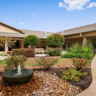 A serene garden courtyard with a small fountain and well-maintained landscaping.