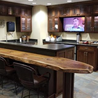A modern kitchen area featuring a wooden counter, bar stools, and a flat-screen TV, perfect for casual gatherings.