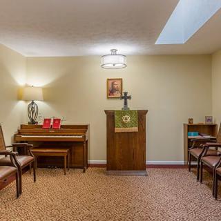 A small chapel with a piano, podium, and seating area.