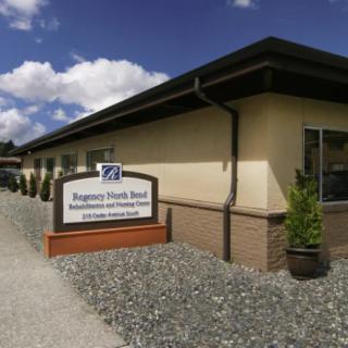 An exterior view of a health center with a sign displaying its name, set against a backdrop of a blue sky with clouds.