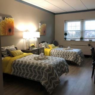 A cozy bedroom with twin beds, decorated with yellow accents and modern artwork.