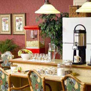 A cozy dining area featuring a coffee maker, popcorn machine, and table set with glasses and cups.