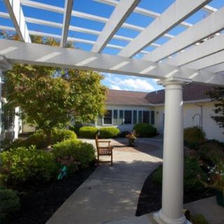 A scenic outdoor courtyard with a pergola and lush greenery.