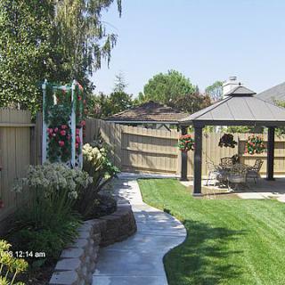 A beautiful backyard with a gazebo, landscaped lawn, and garden path.
