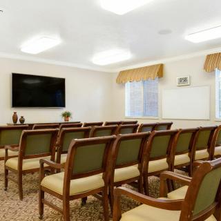 A well-lit conference room with rows of chairs facing a mounted television.