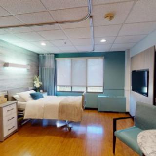 A modern hospital room with a single patient bed and medical equipment.