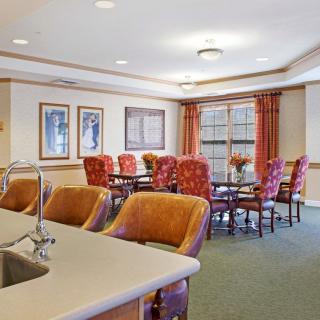 A well-furnished dining and meeting area with upholstered chairs and a large table, featuring ample natural light from the windows.
