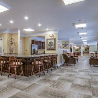 A spacious and modern lounge area with a bar, stools, and comfortable seating.