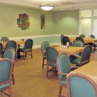 A spacious dining room with multiple tables and chairs, featuring elegant wall decor and warm lighting.