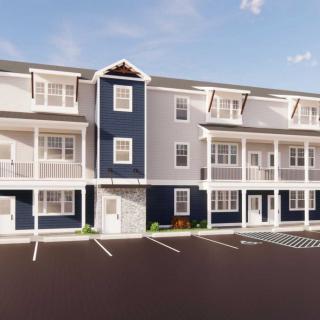 A modern three-story apartment building with balconies and a parking lot.