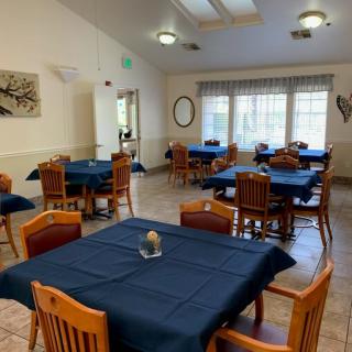A cozy dining area with neatly arranged tables and chairs, adorned with blue tablecloths.