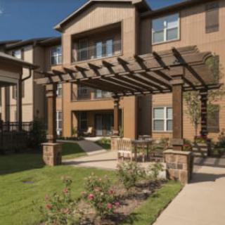 A modern apartment building with a pergola and landscaped garden.