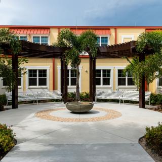 A scenic courtyard with palm trees and a central architectural feature in front of a building.