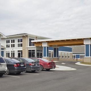 A modern commercial building with an adjacent parking lot filled with cars.