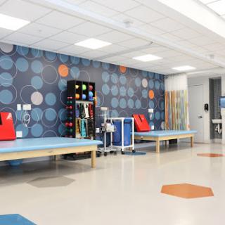 A brightly colored therapy room designed for rehabilitation, featuring equipment and spacious treatment areas.