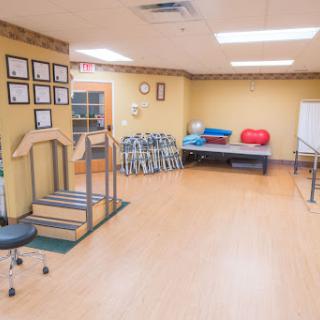 A spacious rehabilitation therapy room equipped with various exercise tools and comfortable seating areas.