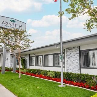 A neatly landscaped view of a building with a prominent sign and flowering plants.
