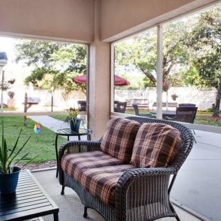 A cozy patio with comfortable wicker furniture and a view of a lush garden.