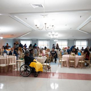 A large group of people gathered indoors, seated at tables for an event.