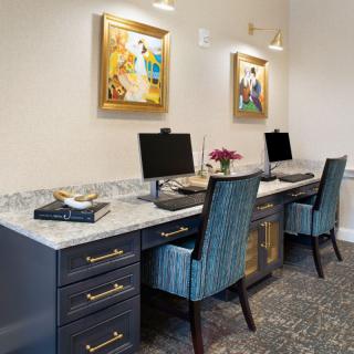 A modern office workspace with two computers, comfortable chairs, and decorative artwork on the walls.