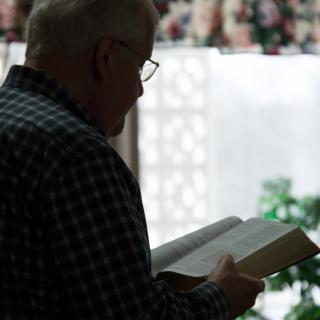 A person reading a book indoors in silhouette.
