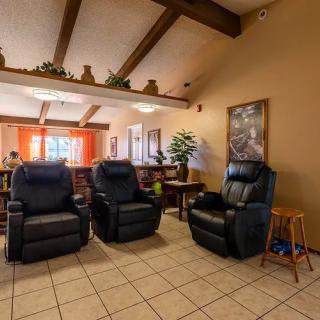 A cozy living room with three black recliners and warm lighting.