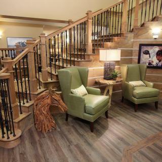 Cozy living area with green armchairs and a wooden staircase.