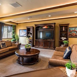 A cozy living room with warm lighting, featuring comfortable seating and a large entertainment center.