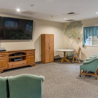 A cozy living room with a television, comfortable chairs, and a wooden cabinet.