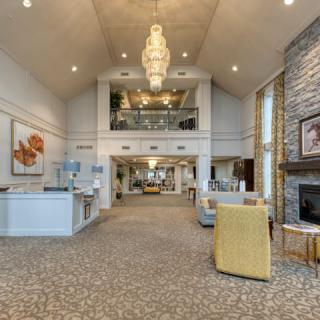 A spacious and modern lobby with a chandelier, fireplace, and seating area.
