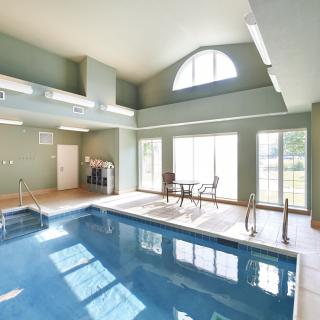 A bright indoor swimming pool area with large windows and a seating area.